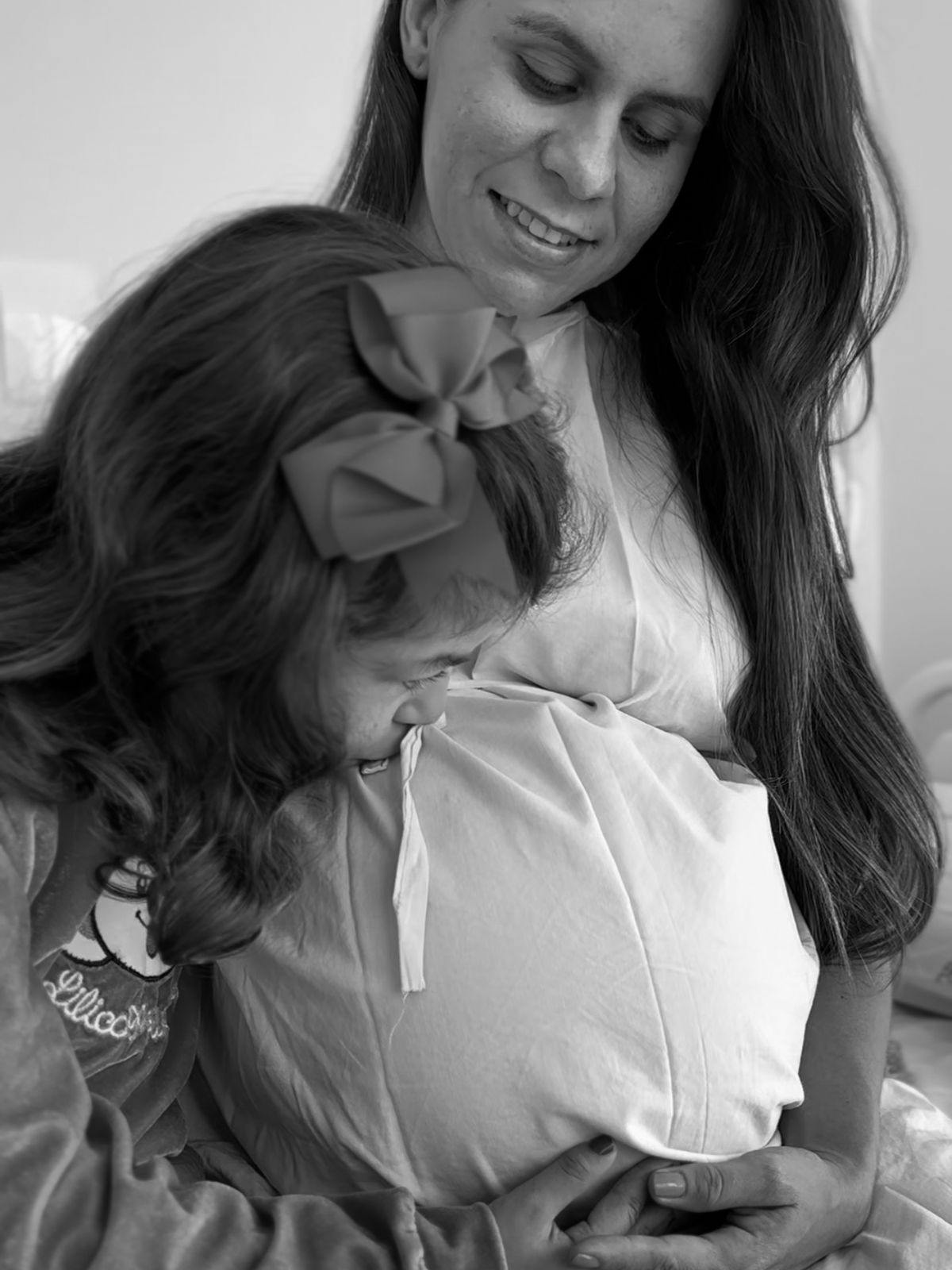 Foto de uma criança beijando a barriga da mãe